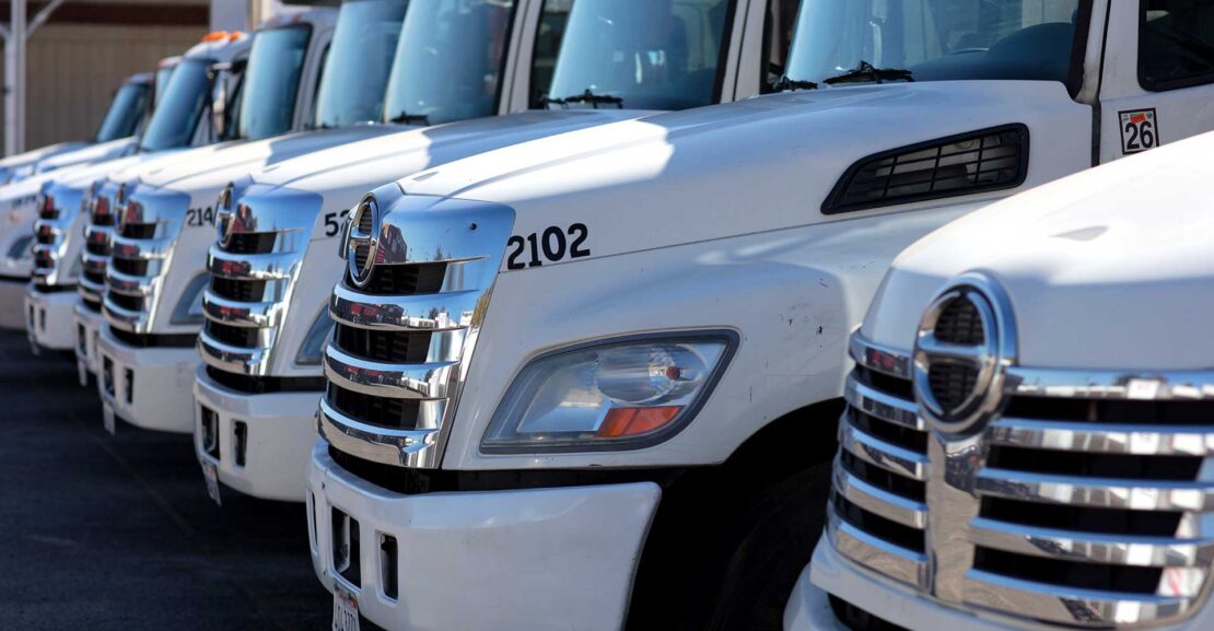 Row of front grills of white commercial trucks