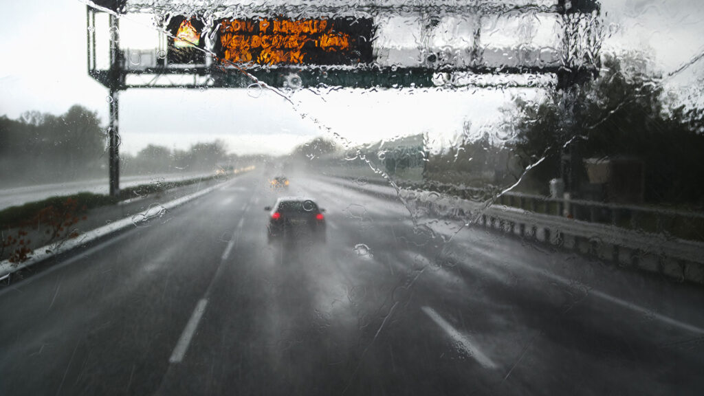 A rain storm road from the view of a trucker's cockpit