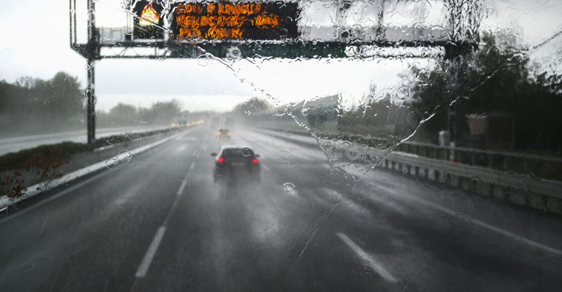 A rain storm road from the view of a trucker's cockpit