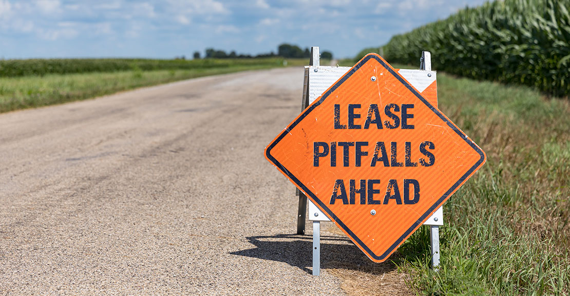 Caution sign on side of road that reads "Lease pitfalls ahead"