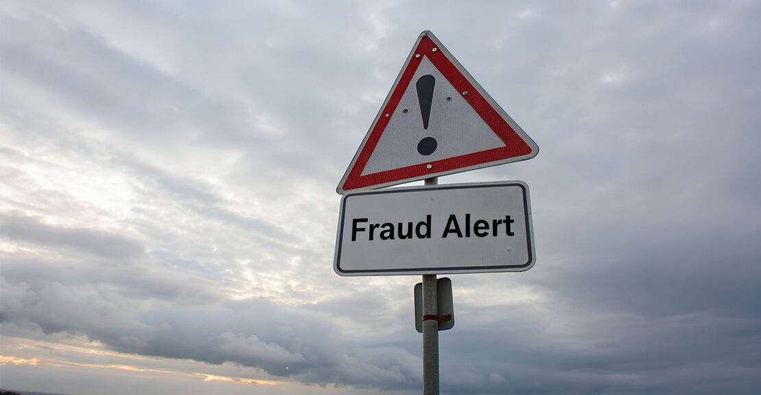 Fraud alert road sign under ominous sky