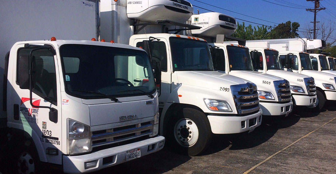 Row of white Suppose U Drive commercial trucks, in a variety of types and styles.