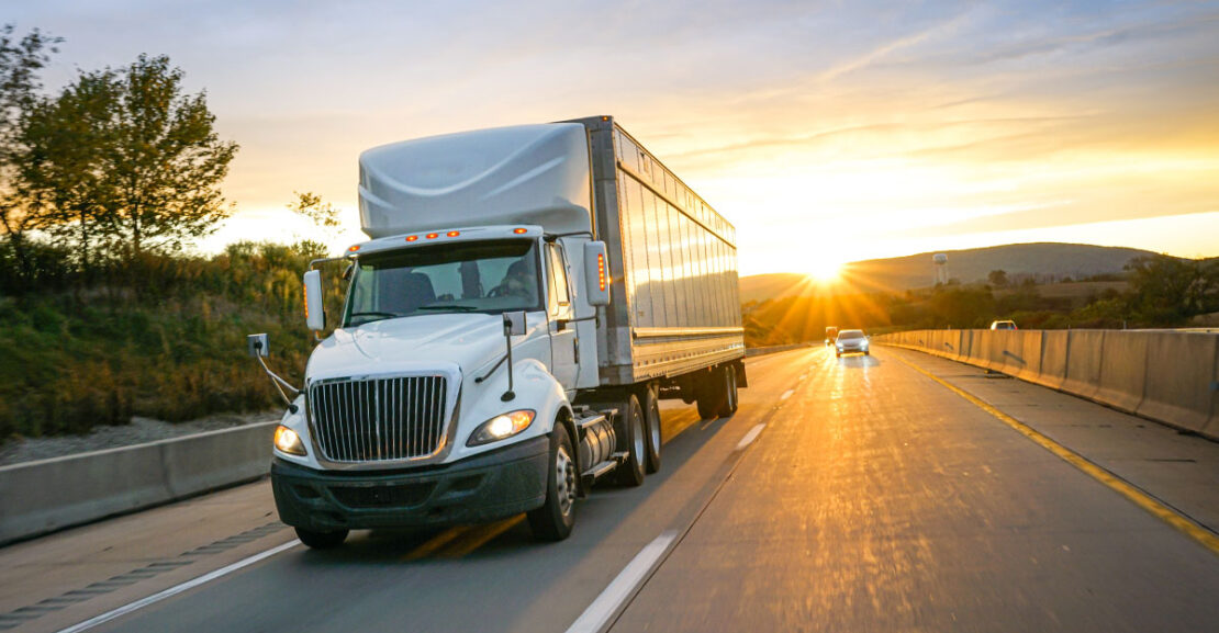 White semi truck on highway at sunset