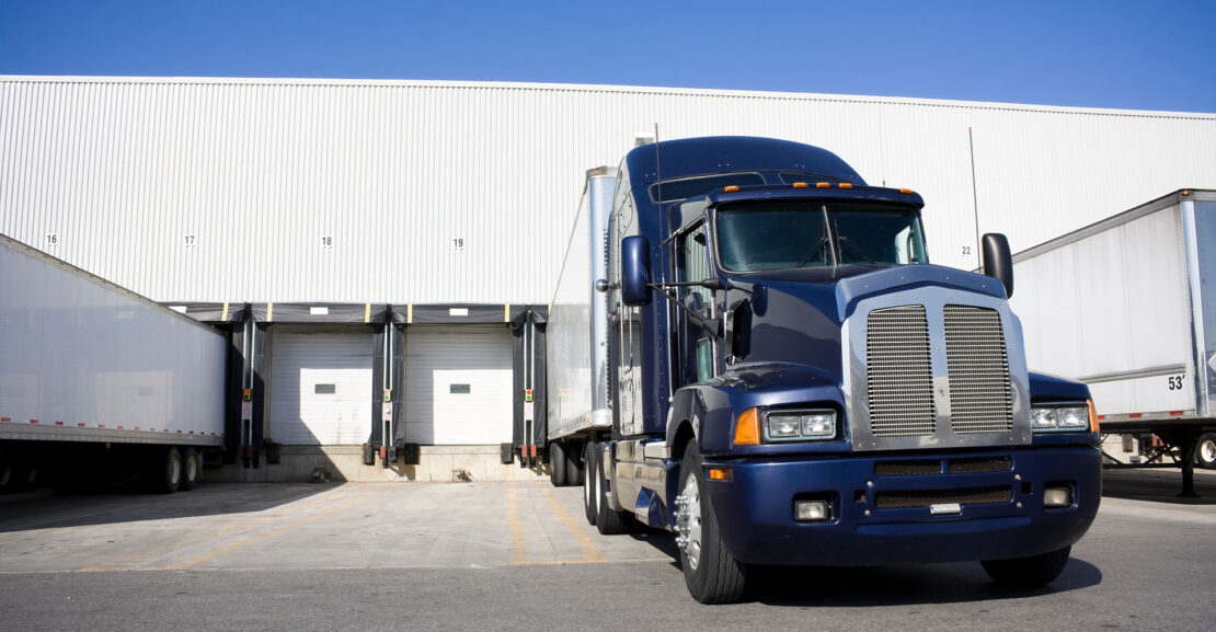 Blue tractor trailer docking in warehouse