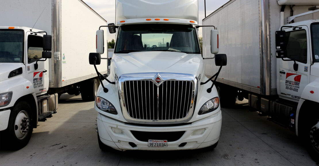 Row of white semi trucks and Box Trucks from the front