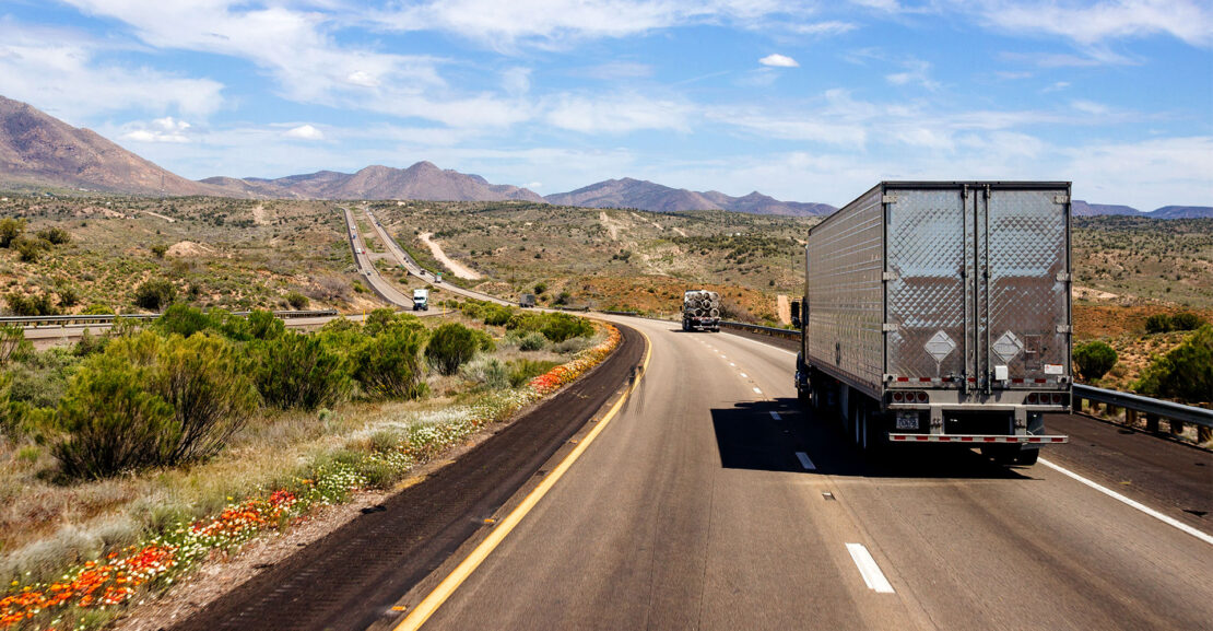 Box truck on a beautiful blue sky with fluffy clouds over the highway on a spring day.