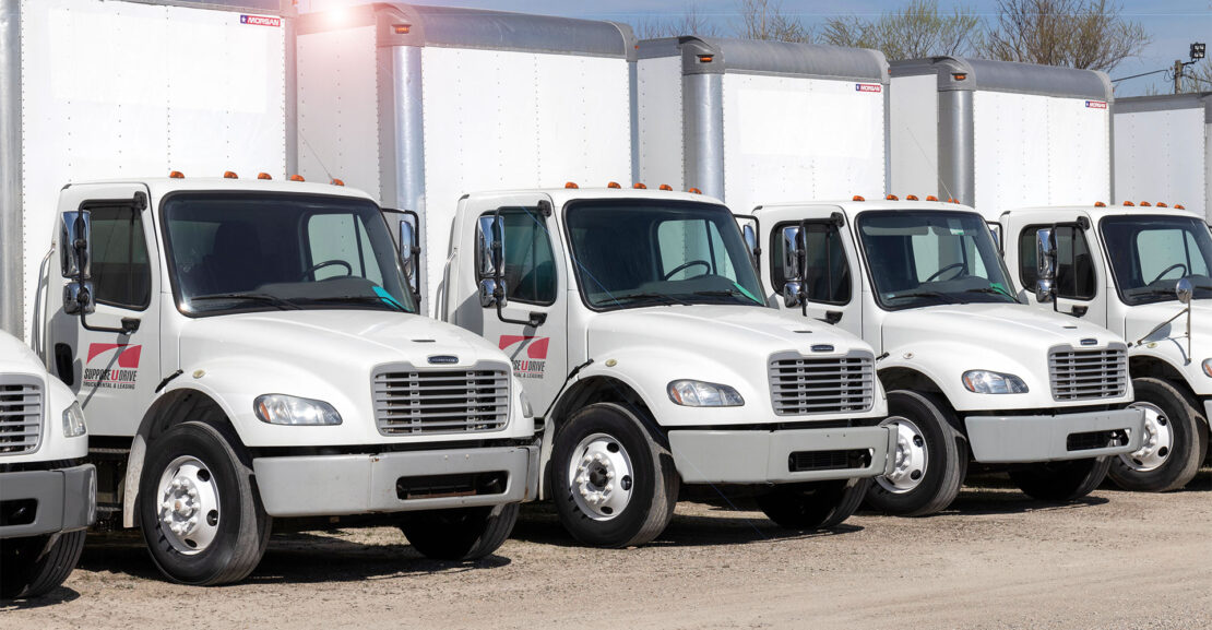 Row of Medium Duty box trucks under hot sun