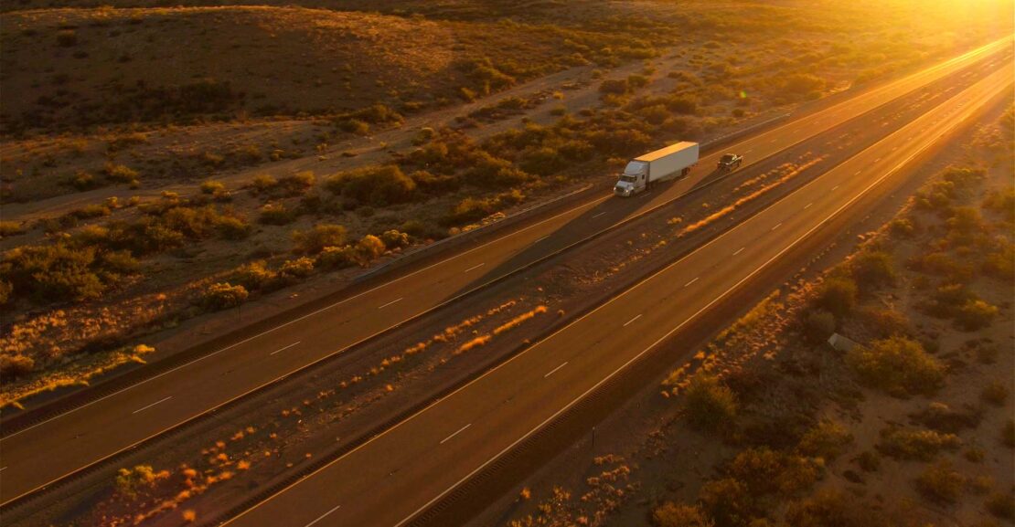 Aerial photo of Cars and semi trucks driving on busy highway at summer sunset