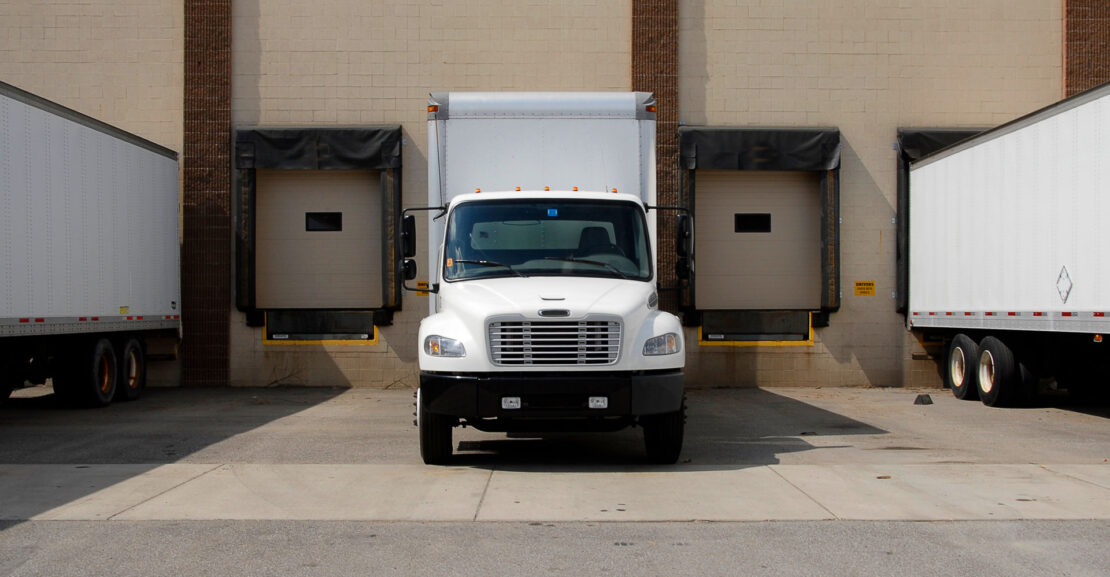 Front view of white box tuck backed up to a loading dock